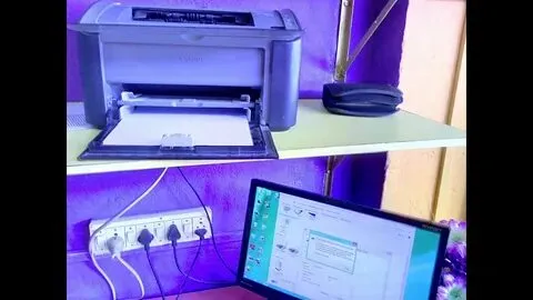 Computer connected to a printer via USB, showing setup process on screen for how to install printer driver easily at home.