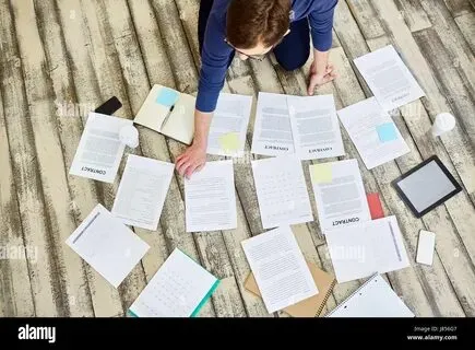 Person sorting through papers and contracts, asking can I print personal documents at work without breaking rules?